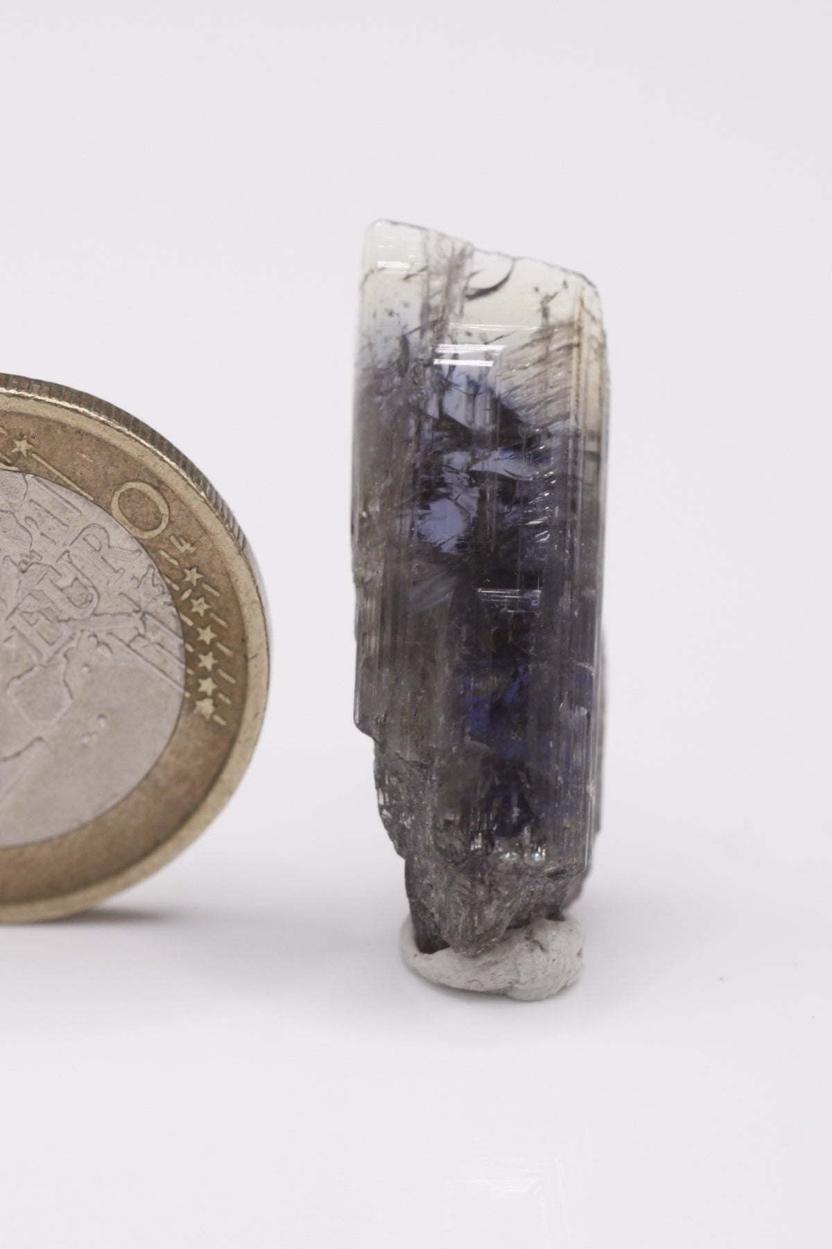 Tanzanite - Mine Mineral Market : A009 Ein violetter Doppelender mit sehr guter Endfläche oben und gutem Pleochroismus, seitlich in einem kleinen Bereich etwas Graphit aufsitzend.