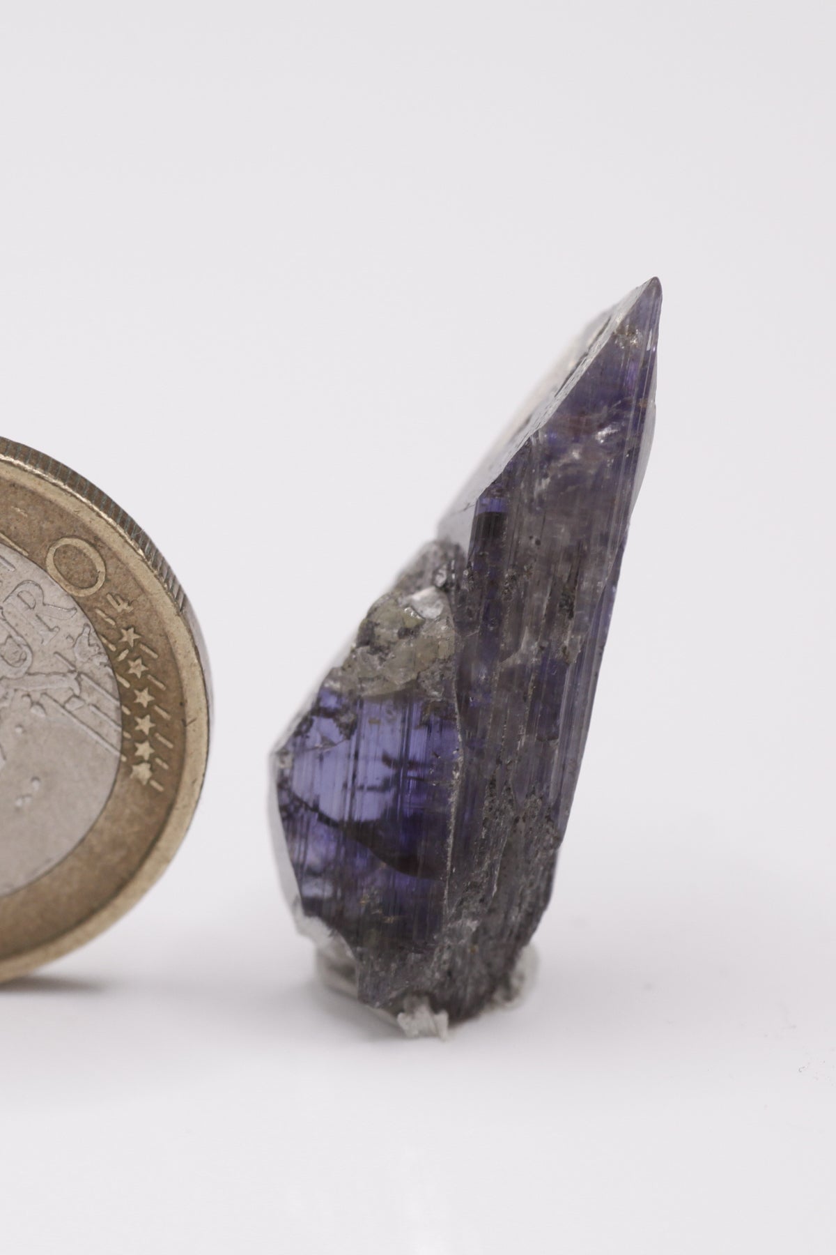 Tanzanite - Mine Mineral Market : A009 Ein violetter Doppelender mit sehr guter Endfläche oben und gutem Pleochroismus, seitlich in einem kleinen Bereich etwas Graphit aufsitzend.