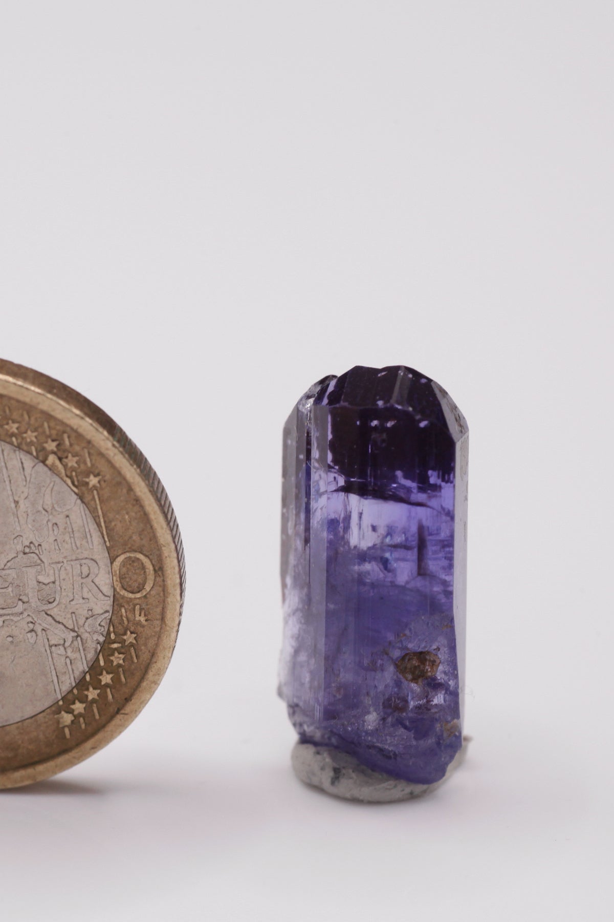 Tanzanite  - Mine Mineral Market :    A035 Ein vollständiger klarer Kristall (im oberen Teil von Facettierqualität) mit hervorragenden Endflächen, auf der Rückseite teilweise mit Alabandin überzogen, sonst sehr guter Glanz.