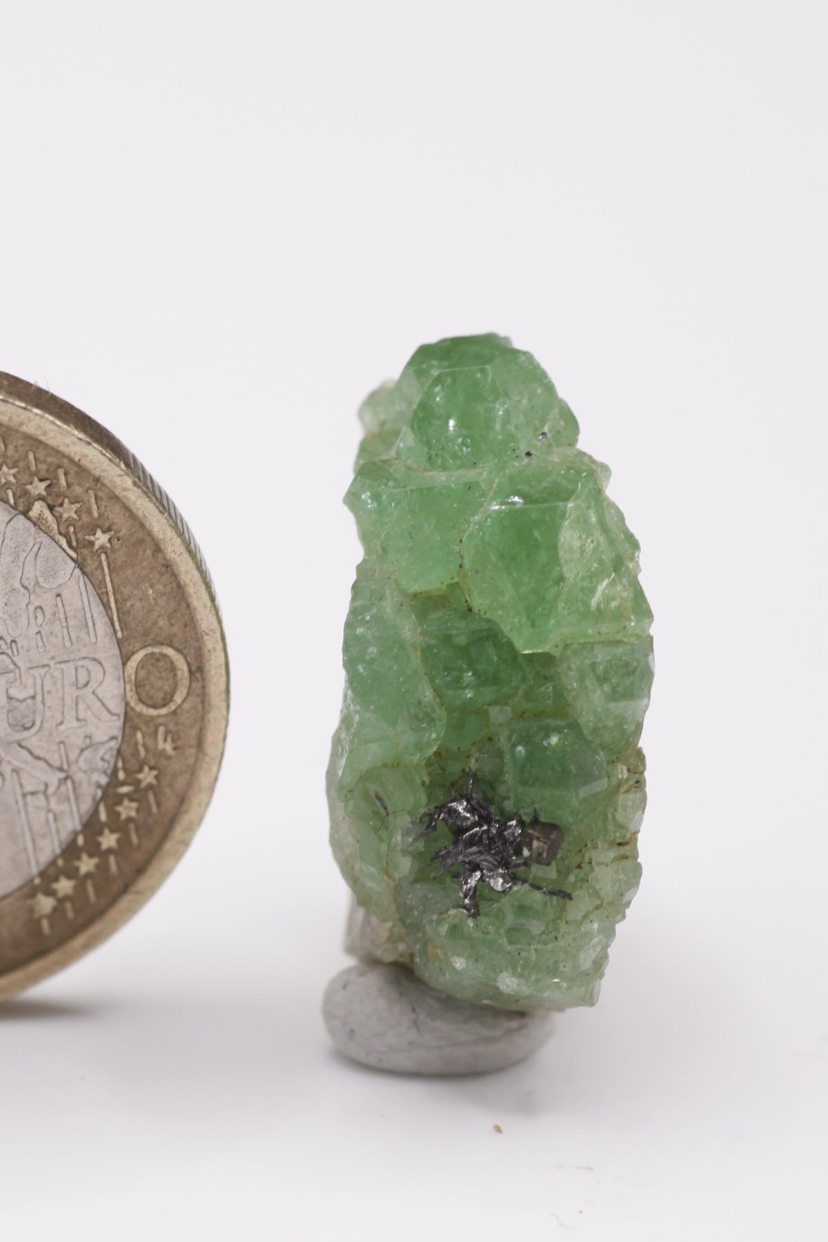 Tsavorite - Mine Mineral Market : A061 Eine kleine Stufe von Tsavorit-Kristallen mit gutem Glanz. In einer kleinen Höhle sitzen Graphitkristalle.