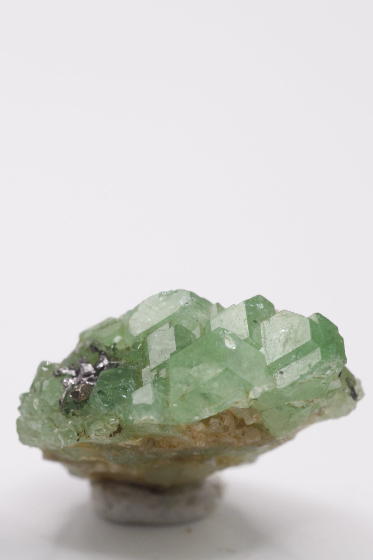 Tsavorite - Mine Mineral Market : A061 Eine kleine Stufe von Tsavorit-Kristallen mit gutem Glanz. In einer kleinen Höhle sitzen Graphitkristalle.