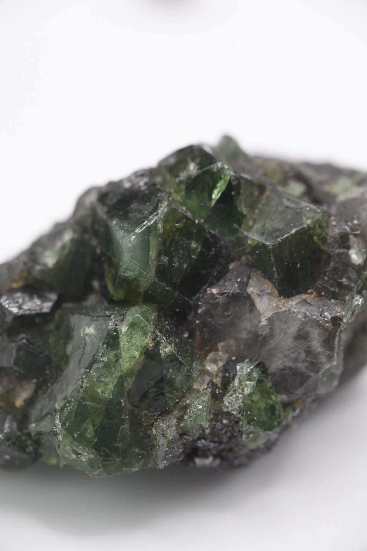 Tsavorite - Mine Mineral Market : A072 Ein großer dunkler Tsavoritkristall mit etwas Graphit und recht gutem Glanz.