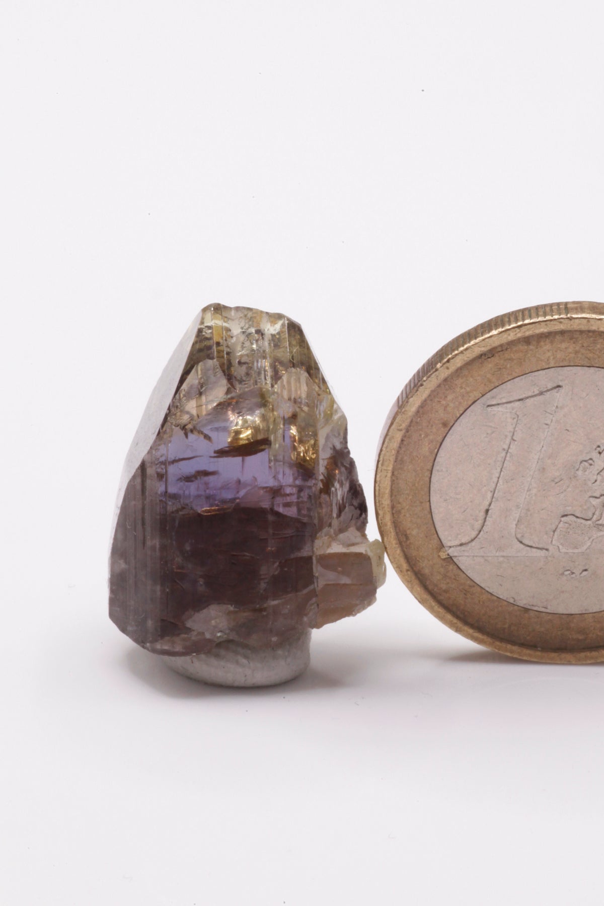 Tanzanite - Mine Mineral Market : A232 Wir erhielten ein Tansanitlot aus Altbeständen eines sightholders der seit 2015 geschlossenen Tanzanite One mining Gesellschaft. Dieser gut glänzende Kristall ist zweifarbig, oben gelb und in der Mitte klassisch grau bzw. blauviolett. An der Seite etwas Graphit und Diopsid sowie eine Beschädigung.