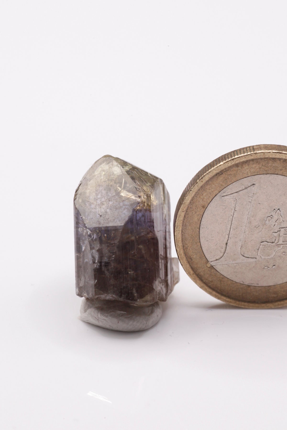 Tanzanite - Mine Mineral Market : A232 Wir erhielten ein Tansanitlot aus Altbeständen eines sightholders der seit 2015 geschlossenen Tanzanite One mining Gesellschaft. Dieser gut glänzende Kristall ist zweifarbig, oben gelb und in der Mitte klassisch grau bzw. blauviolett. An der Seite etwas Graphit und Diopsid sowie eine Beschädigung.