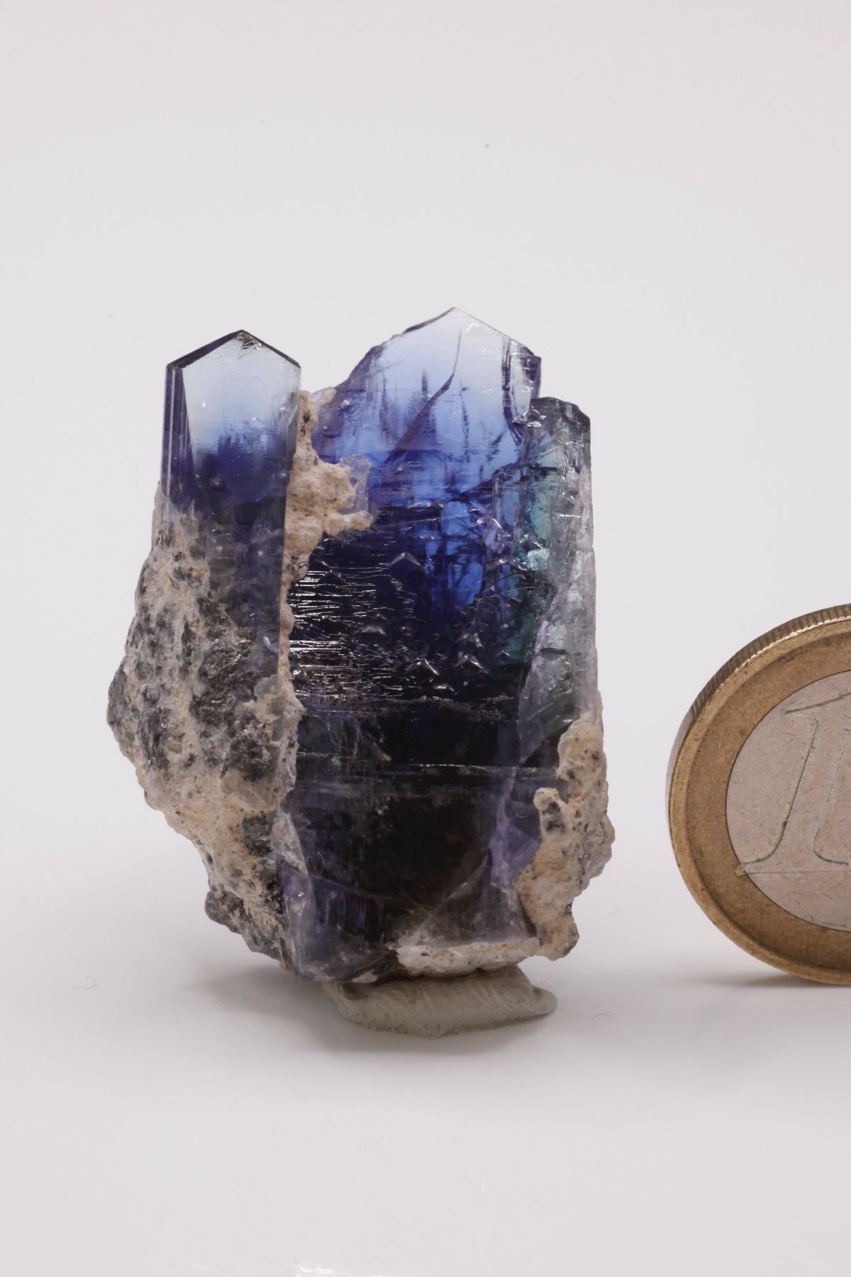 Tanzanite - Mine Mineral Market : A234 Zwei kräftig blaue Tansanite, etwas versetzt voneinander zusammengewachsen, bilden so eine sehr ansprechende Tansanit-Stufe. Die Spitzen sind bis auf eine kleine Beschädigung seitlich an der breiteren Spitze vollständig. Guter Glanz, seitlich unten Matrixanhaftungen.