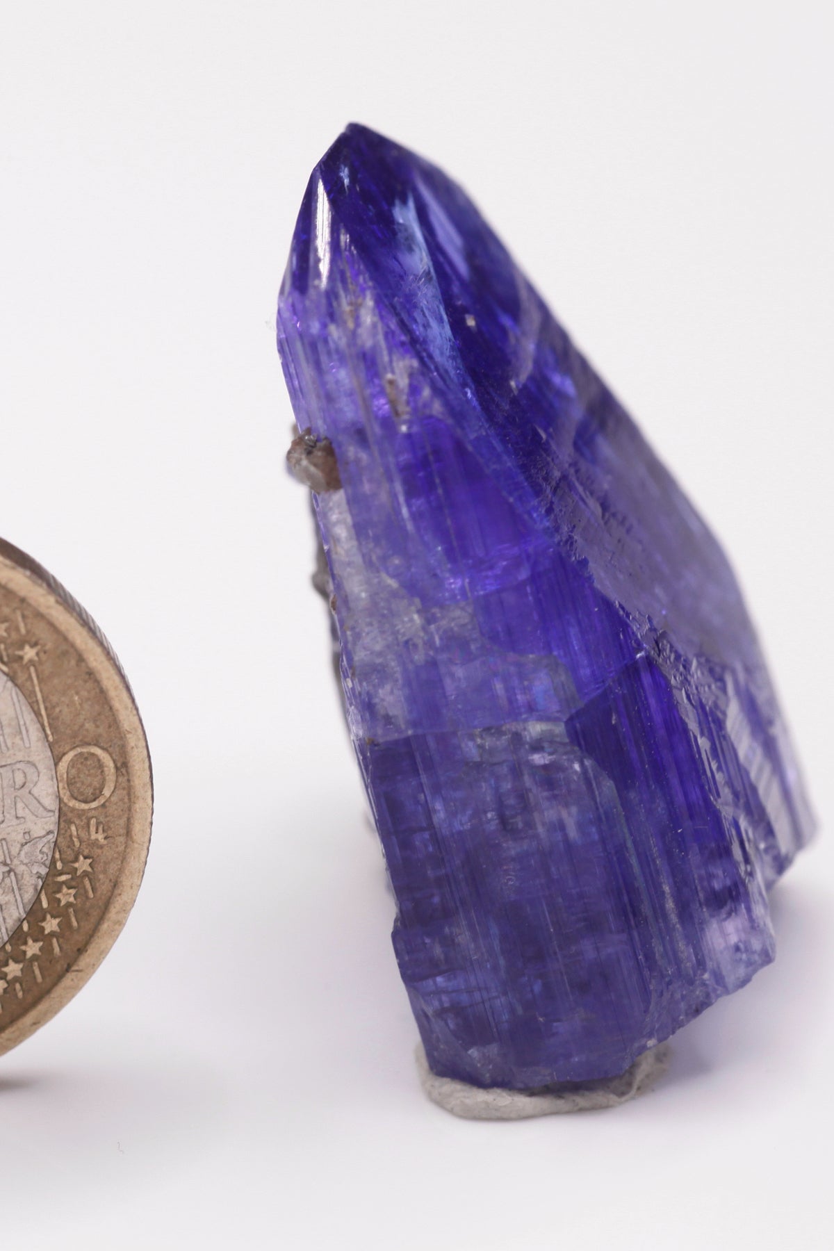 Tanzanite  - Mine Mineral Market :    A028 Ein größerer transparenter und unbeschädigter Kristall von schöner tiefblauer Farbe, mit etwas Matrix (Graphit & Diopsid) und sehr gutem Glanz.  