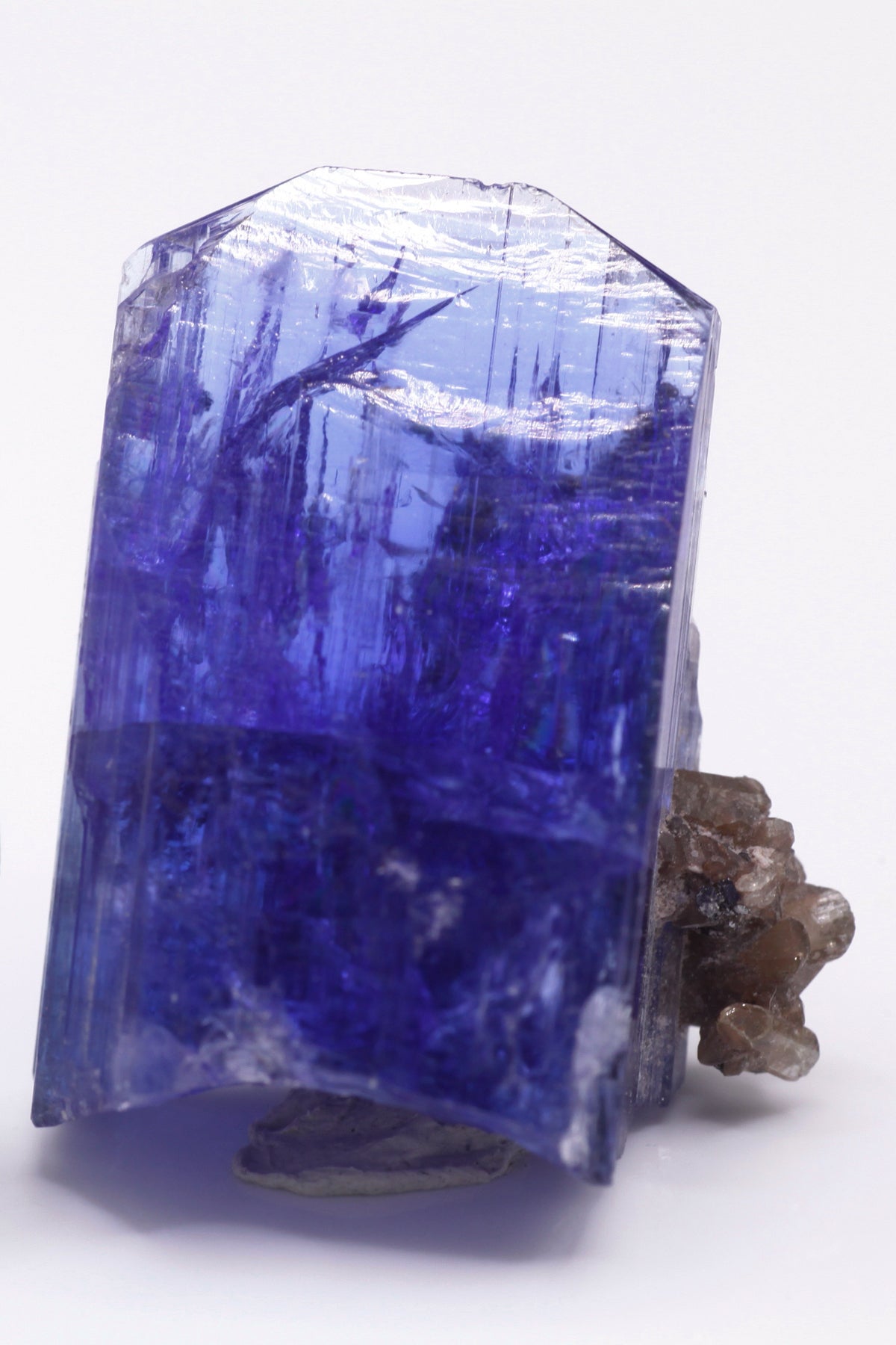 Tanzanite  - Mine Mineral Market :    A028 Ein größerer transparenter und unbeschädigter Kristall von schöner tiefblauer Farbe, mit etwas Matrix (Graphit & Diopsid) und sehr gutem Glanz.  