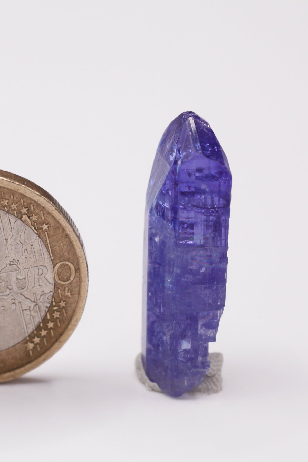 Tanzanite  - Mine Mineral Market :    A033 Dieser schön transparente Kristall war auf einer Seite beim Wachstum eingeengt und bildete deshalb lokal bizarre Prismenflächen aus. Er zeigt dunkelblaue Farbe, sehr gute Endflächen und ebenfalls guten Glanz.  