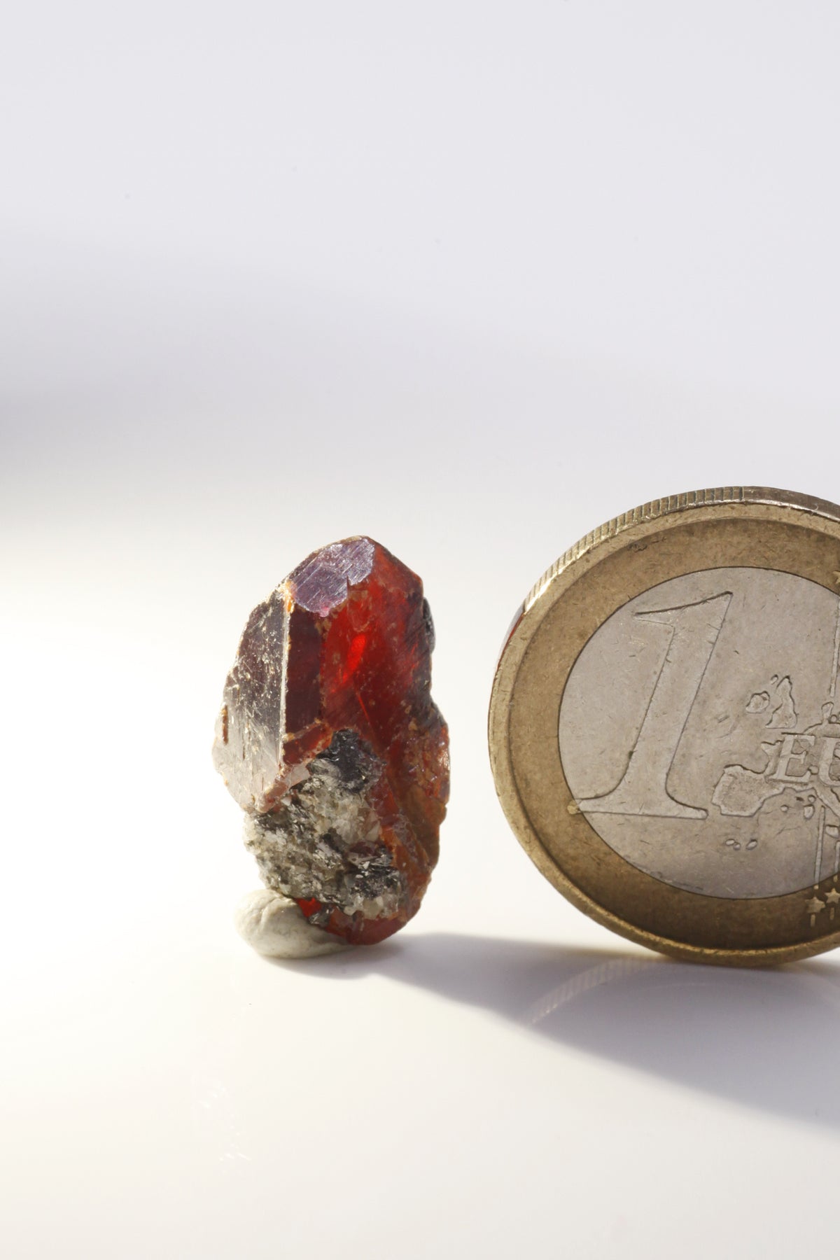 Wurtzite / Sphalerite  - Mine Mineral Market :    A129 Kleiner, länglicher rotbrauner Sphalerit, teilweise mit sehr gut ausgebildeten glänzenden (End-) Flächen. Unten etwas Matrix anhaftend.  