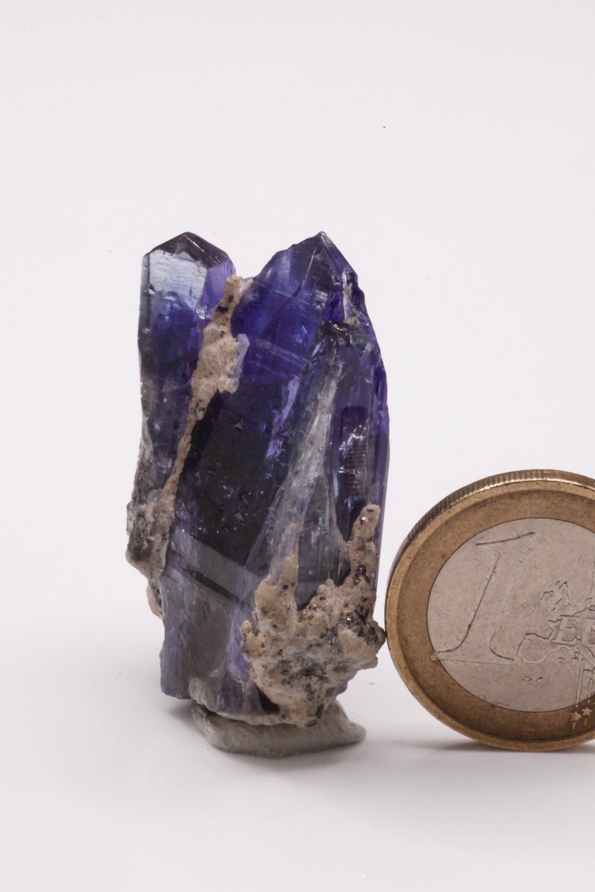 Tanzanite  - Mine Mineral Market :    A234 Zwei kräftig blaue Tansanite, etwas versetzt voneinander zusammengewachsen, bilden so eine sehr ansprechende Tansanit-Stufe. Die Spitzen sind bis auf eine kleine Beschädigung seitlich an der breiteren Spitze vollständig. Guter Glanz, seitlich unten Matrixanhaftungen.  